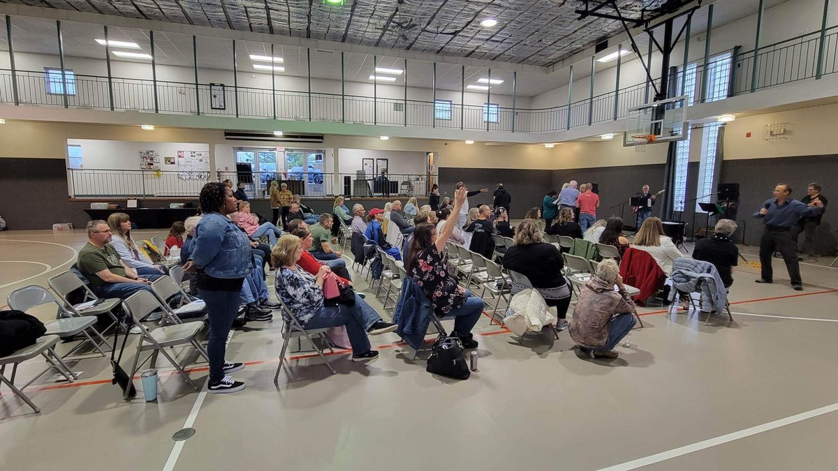 Congregation seated in folding chairs for a Sunday service with the worship team on stage