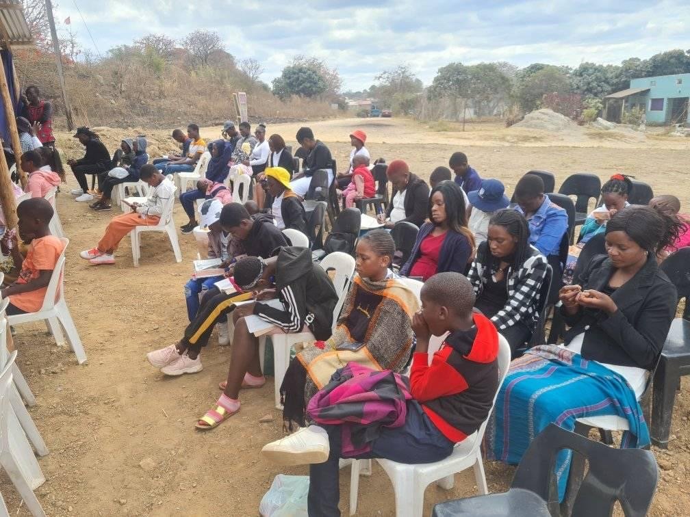Overflow crowd seated outdoors for a service at the Karoi church